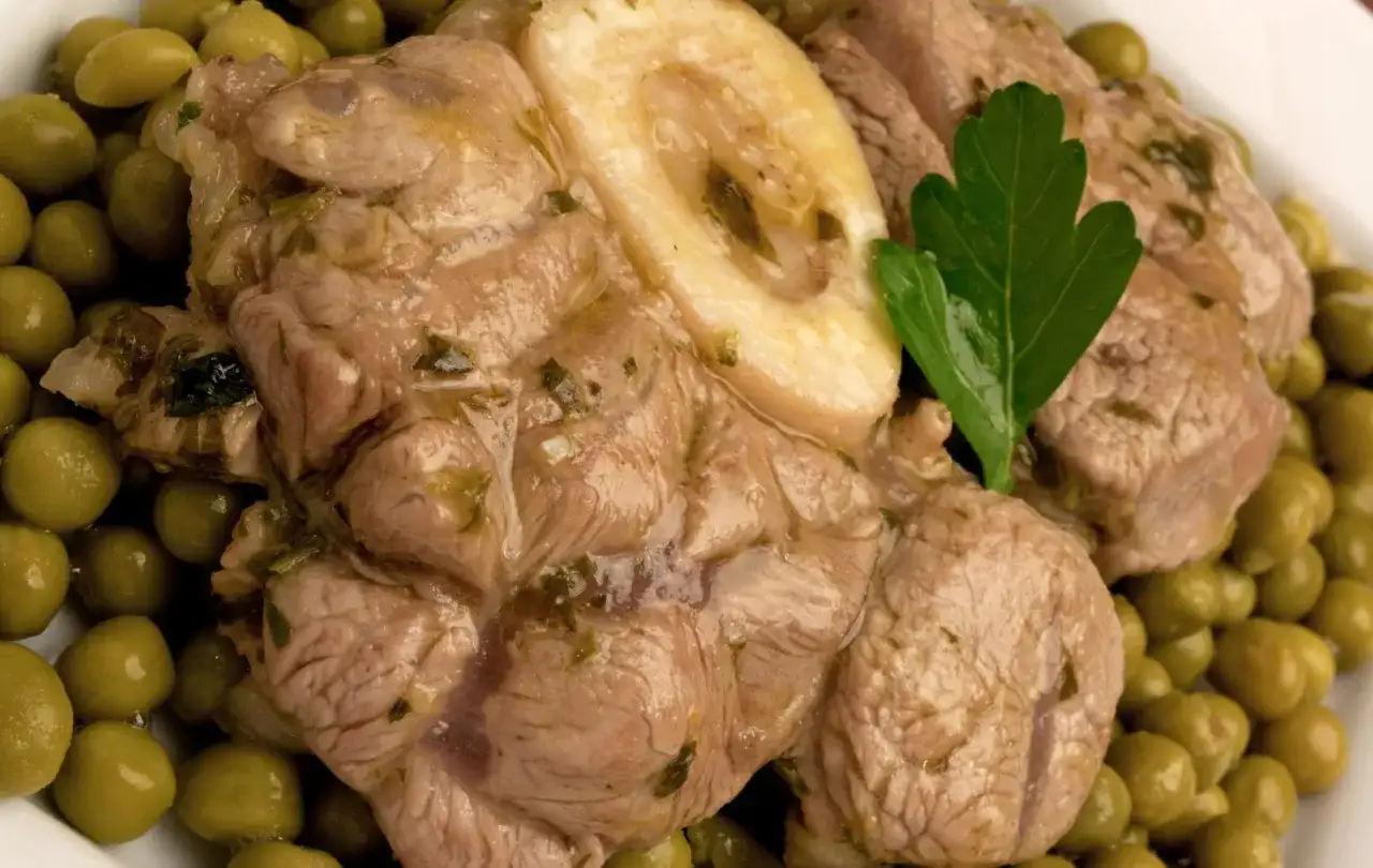 Ossobuco con piselli, un piatto succulento con carne tenera e piselli verdi brillanti, guarnito con una foglia di prezzemolo.