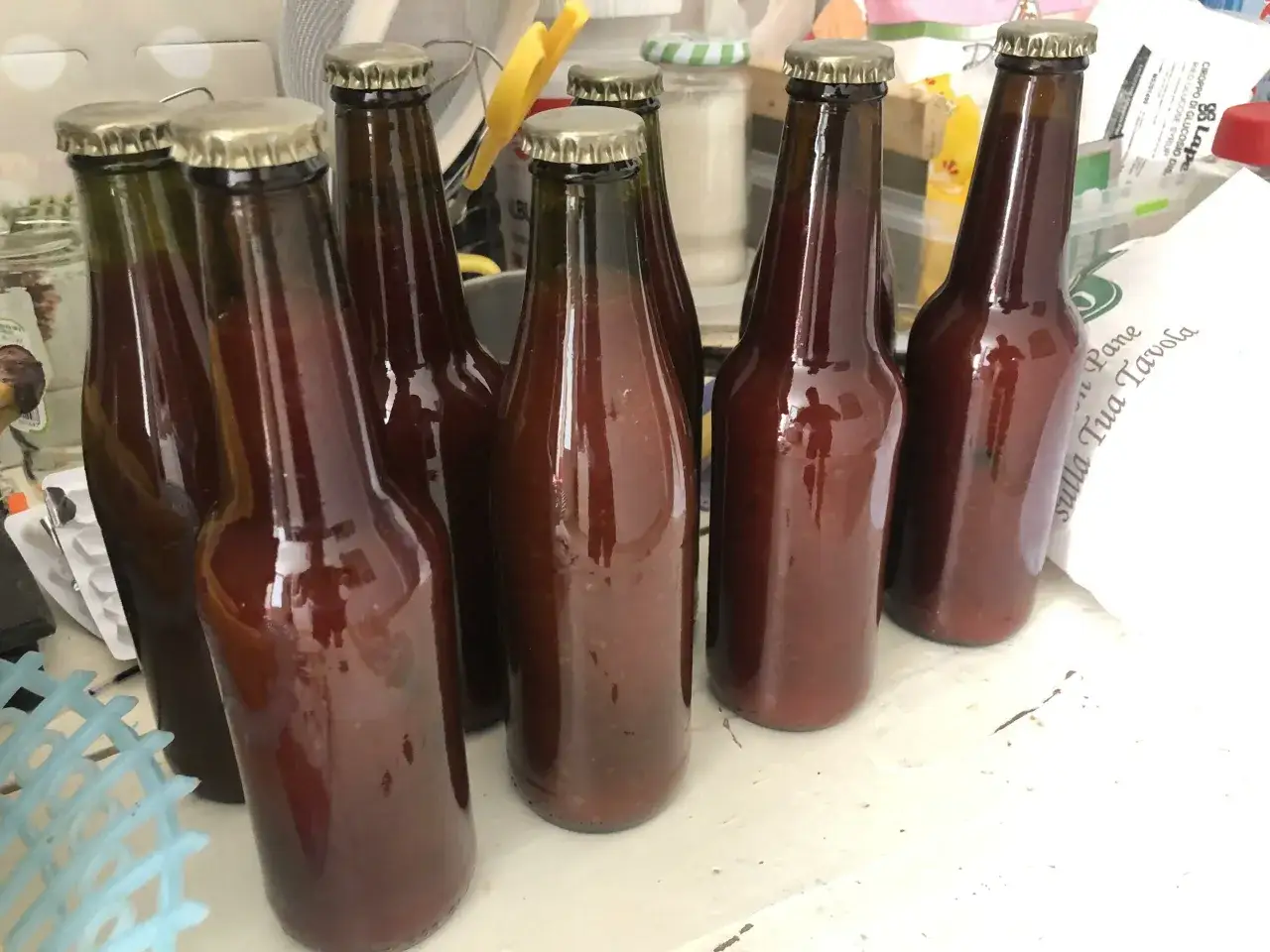 Bottiglie di vetro scuro piene di passata di pomodoro fatta in casa, pronte per essere conservate.