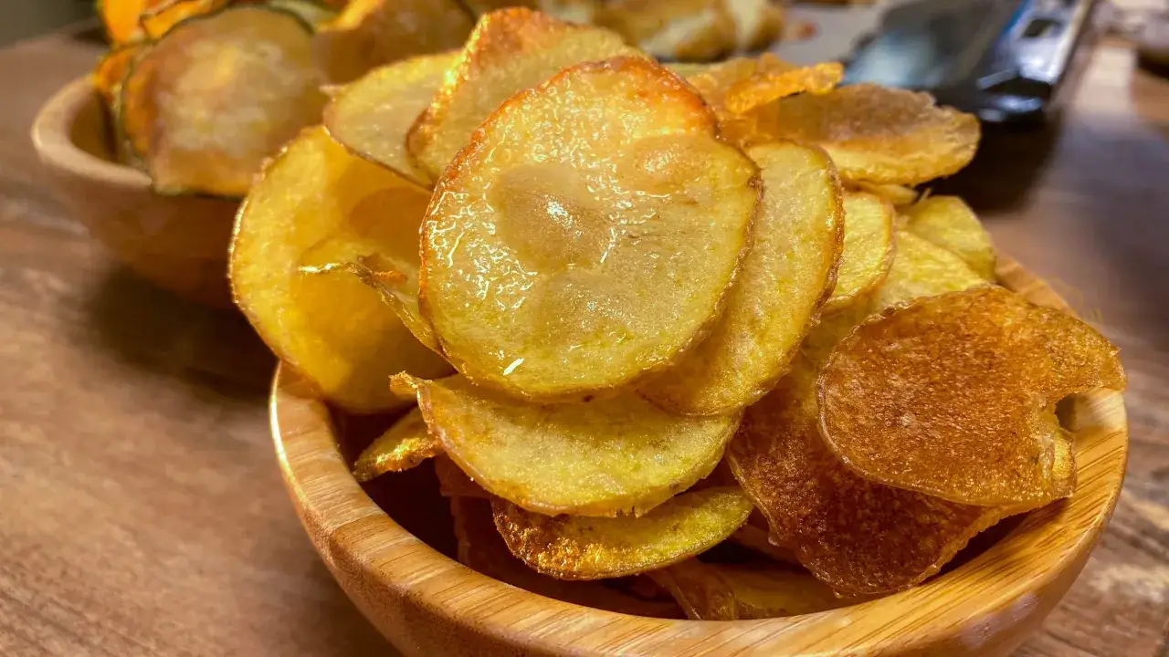 Una ciotola di legno piena di croccanti chips di patate dorate, perfette per uno spuntino.