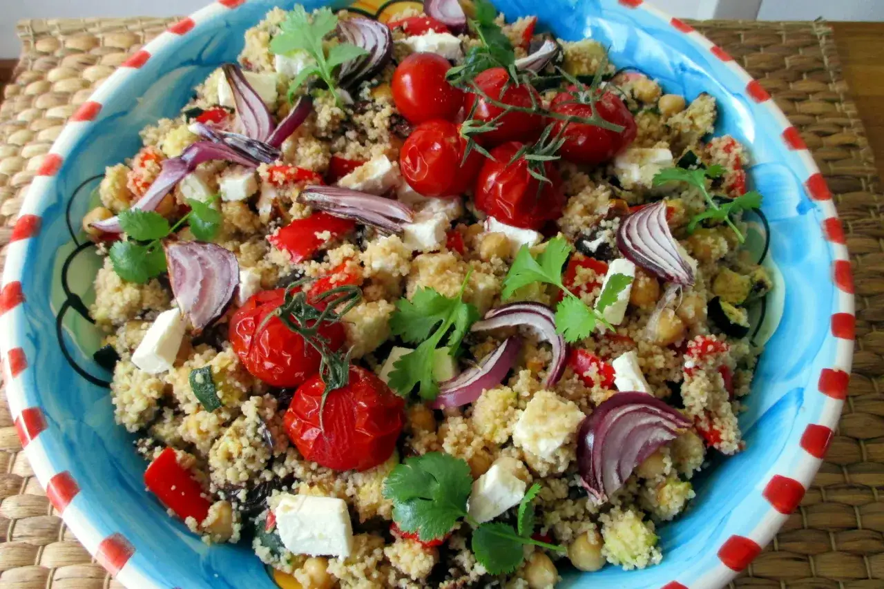 Cous cous colorato con pomodorini, feta, cipolla rossa e ceci. Un'idea fresca su come condire il cous cous per un piatto estivo.