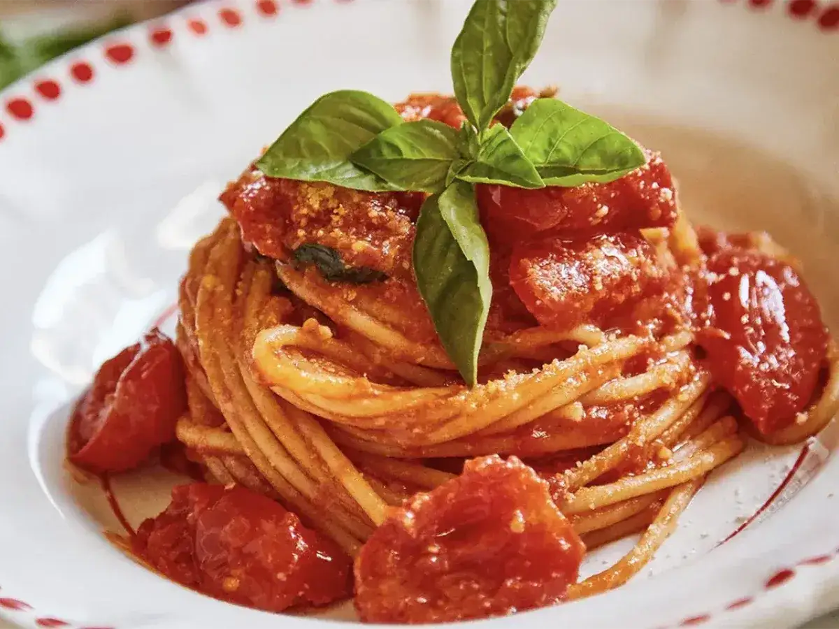 Un piatto invitante di pasta al pomodoro fresco, guarnito con basilico profumato e pomodorini succosi.