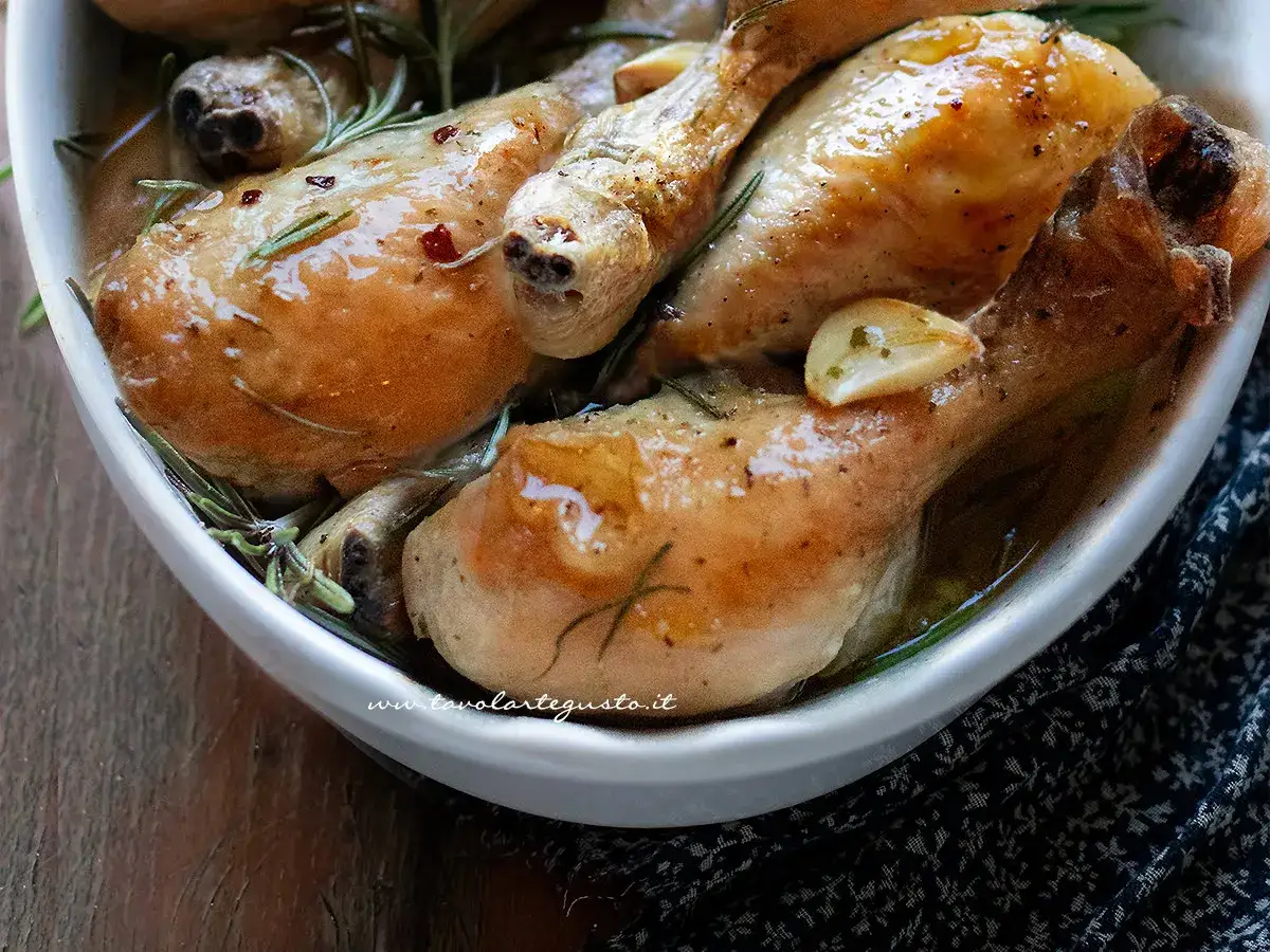 Sovracosce di pollo dorate e succulente, cotte con aglio e rosmarino in una ciotola bianca.