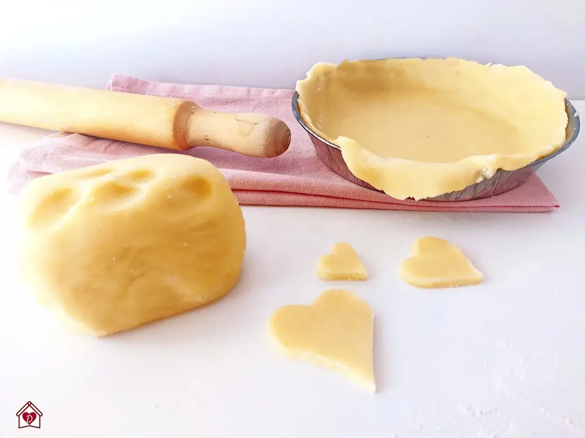 Impasto per pasta frolla senza glutine pronto per essere steso, con cuoricini ritagliati e una base per crostata già foderata.