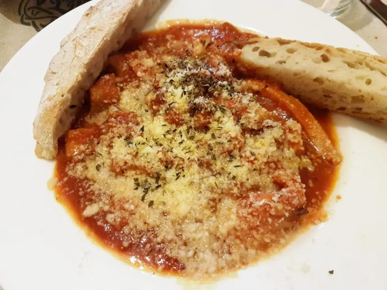 Un piatto di trippa alla romana fumante, con abbondante sugo di pomodoro, formaggio grattugiato e pane croccante.