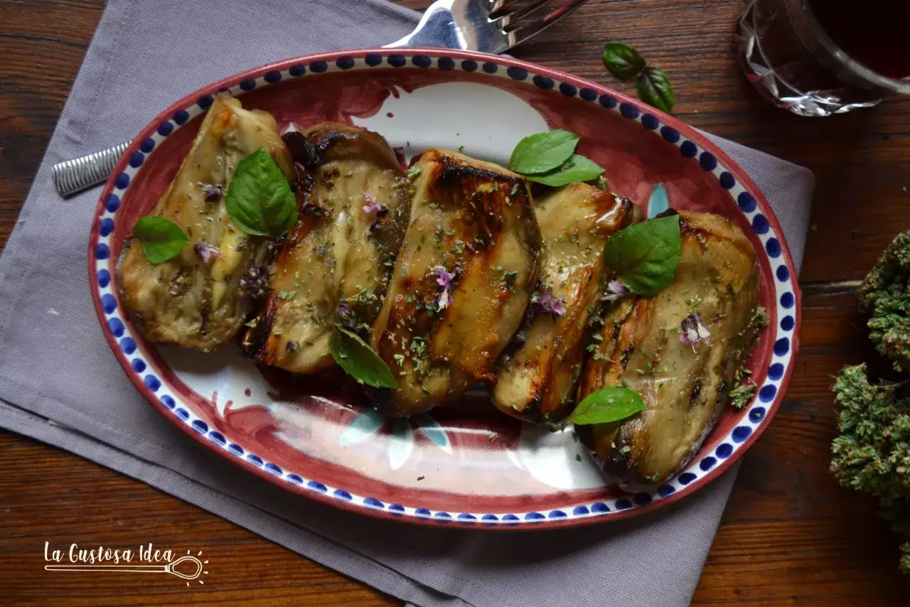 Melanzane in padella, dorate e profumate, guarnite con basilico fresco e erbe aromatiche su un piatto decorato.