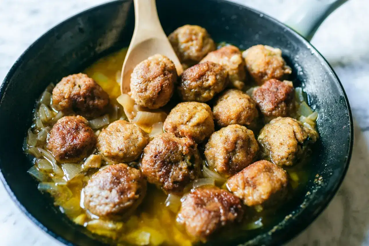 Polpette in bianco dorate e succulente, cotte in padella con cipolle dolci. Un classico confortante pronto da gustare.