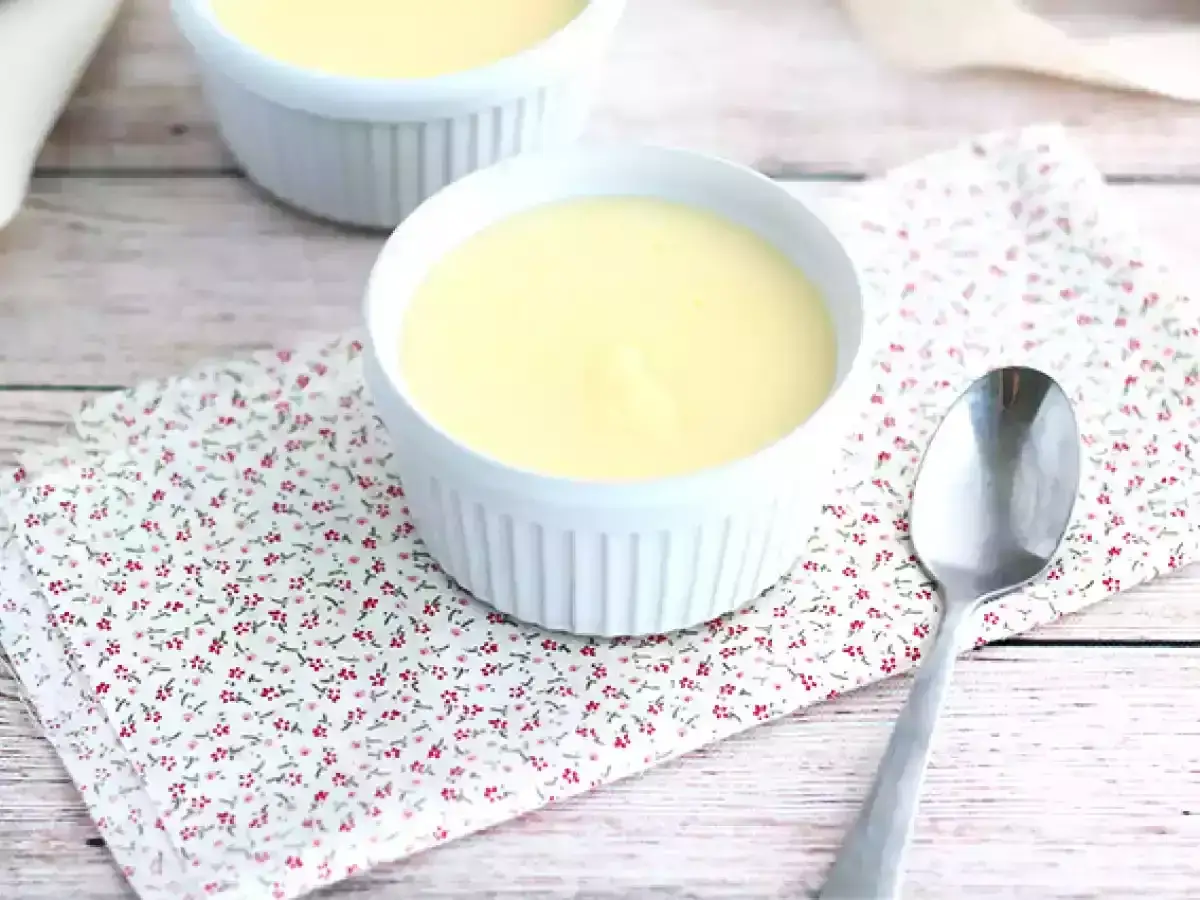 Deliziosa crema al latte in ciotoline bianche, servita su un tovagliolo fiorato con un cucchiaino.