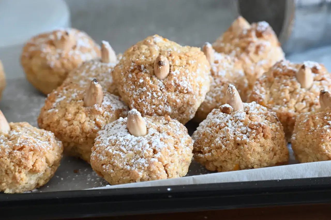 Biscotti alle mandorle morbidi, spolverati di zucchero a velo e decorati con mandorle intere.
