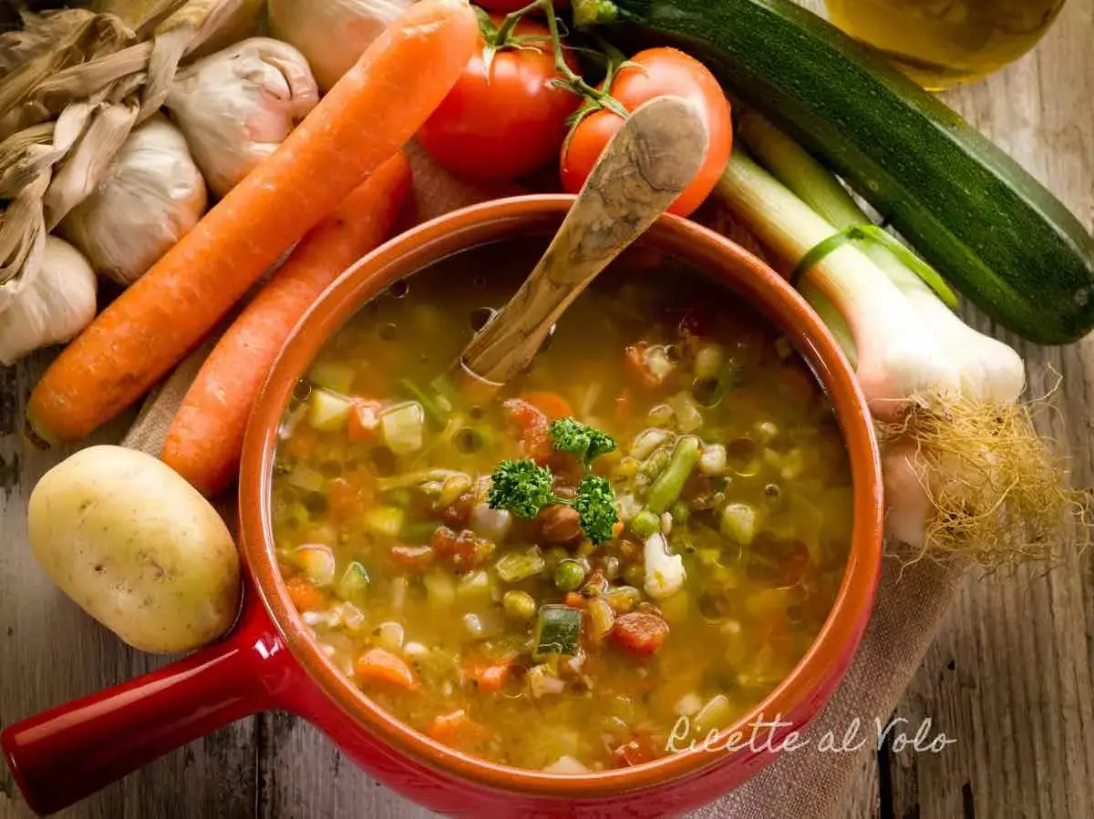 Un fumante minestrone di verdure, ricco di carote, patate, pomodori e zucchine, pronto per essere gustato.