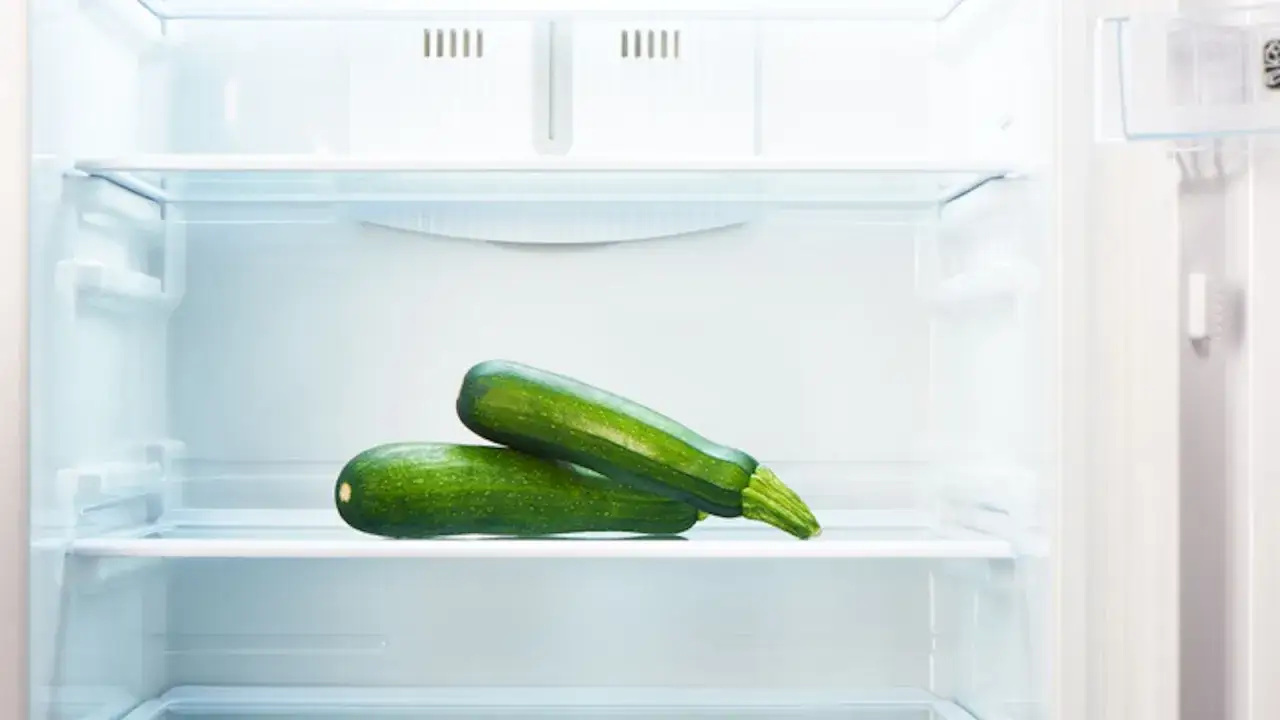 Due zucchine verdi su una mensola del frigorifero, un modo semplice per capire come conservare le zucchine fresche.