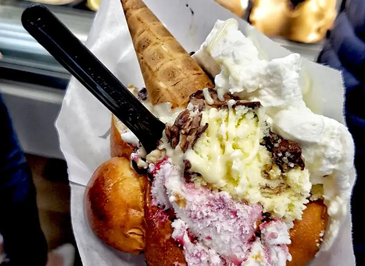 Brioche con gelato, un dolce goloso con panna montata, gelato alla crema e frutti di bosco, e un cono croccante.