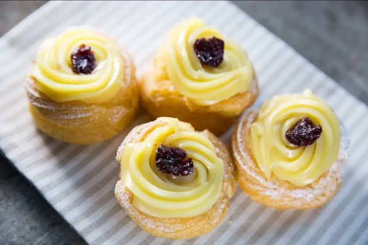Zeppole di San Giuseppe, dolci soffici con crema pasticcera e ciliegia candita, spolverati di zucchero a velo.