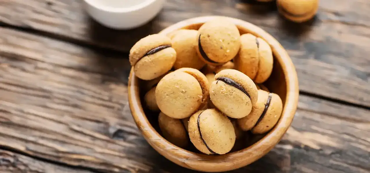 Baci di dama ricetta: deliziosi biscotti alle nocciole con ripieno di cioccolato, pronti per essere gustati.