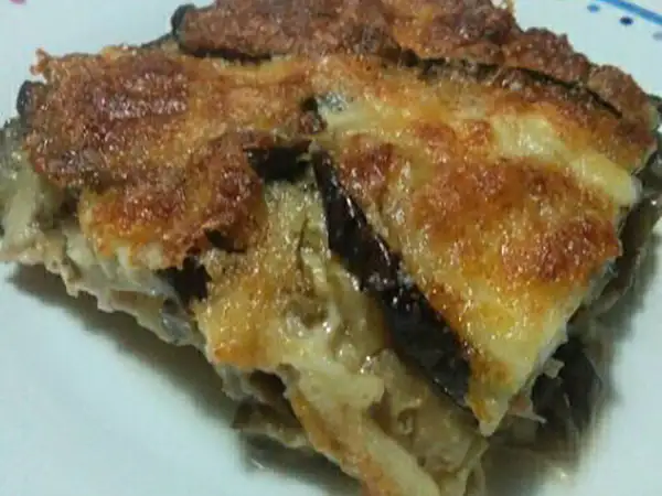 Una fetta di parmigiana di melanzane bianca, dorata e filante, con strati di melanzane e formaggio fuso.