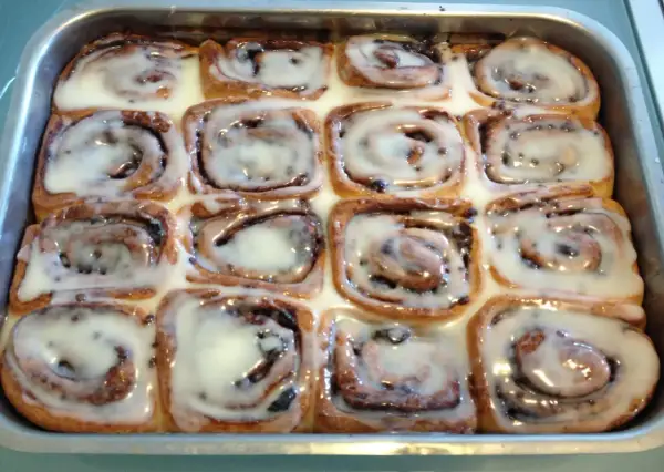 Rotolini alla cannella appena sfornati, ricoperti di glassa bianca e lucida, pronti per essere gustati.
