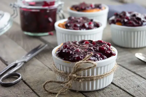 Deliziosa marmellata di amarene ricetta in ciotoline, pronta per essere gustata. Un vasetto pieno e forbici vintage completano la scena.