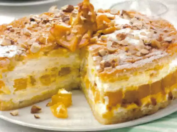 Torta soffice con strati di crema e albicocche, decorata con mandorle e zucchero a velo. Un delizioso tiramisù giallo zafferano.