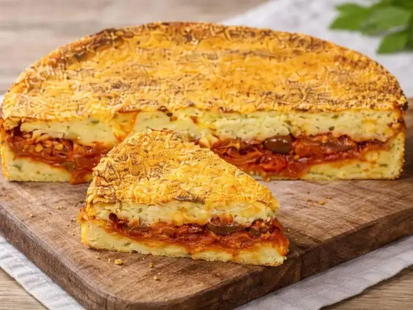 Una fetta di pitta di patate, con strati di ripieno saporito e crosta dorata, pronta per essere gustata.