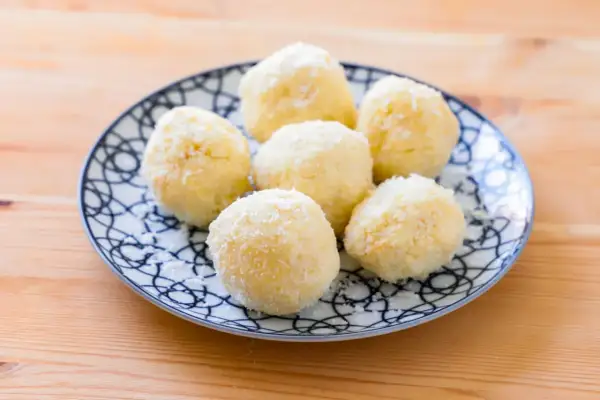Piatto con dolcetti al cocco, soffici e bianchi, su un fondo di legno.