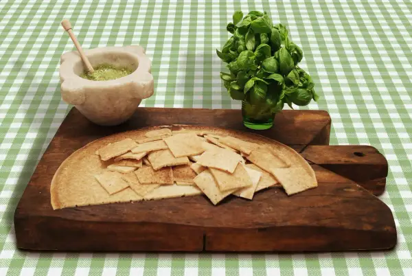 Testaroli al pesto pronti da gustare, con basilico fresco e mortaio.