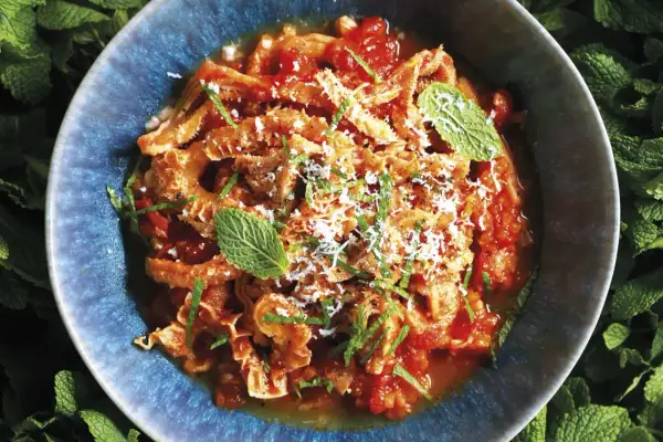 Trippa alla romana in un piatto blu, guarnita con menta e parmigiano. Un classico della cucina romana.